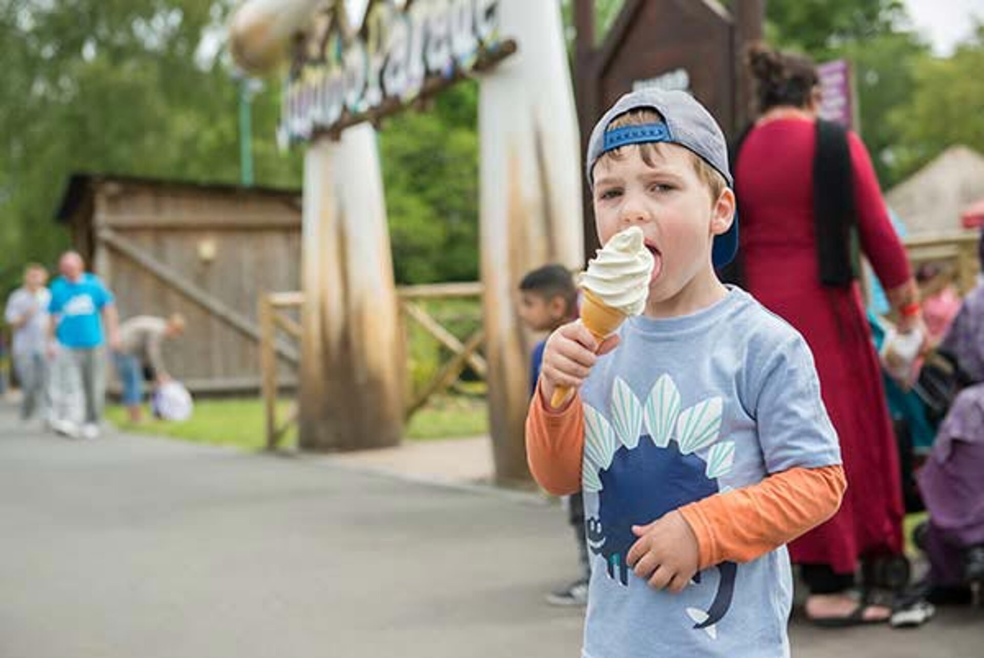 Boy enjoying an ice cream from the Snack Shack at West Midlands Safari Park, smiling while sitting outdoors on a sunny day