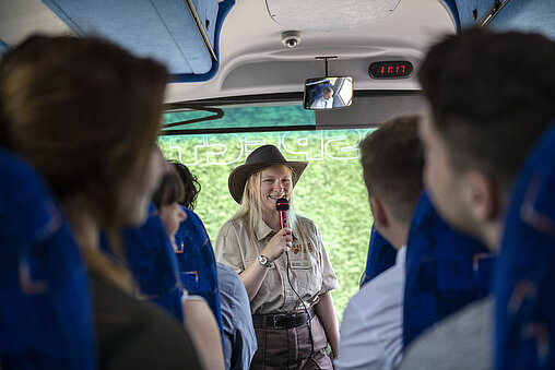 woman speaking at the front of coach during tour with passengers listening at West Midlands Safari Park