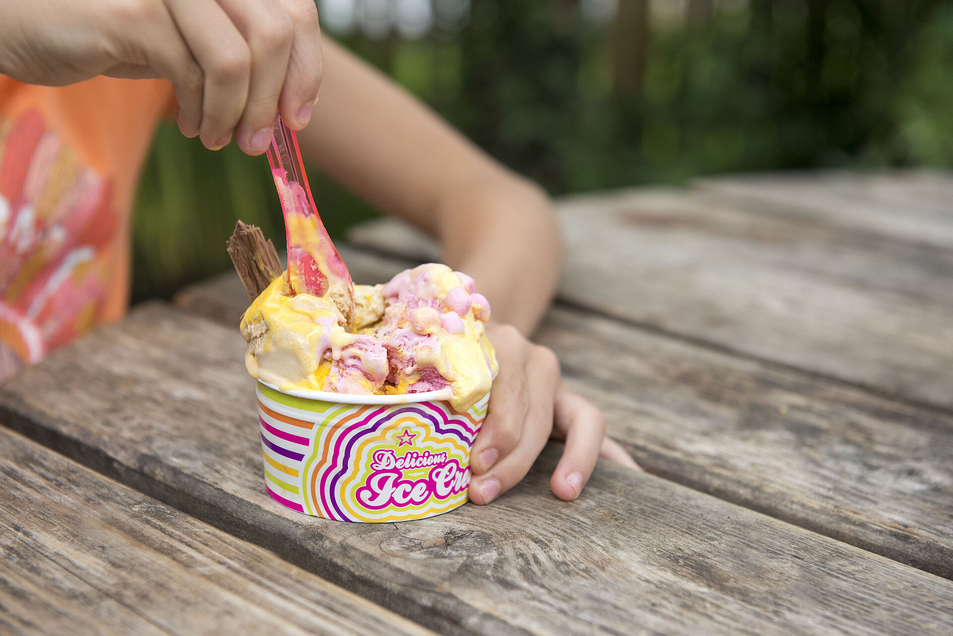 Girl eating ice cream on a bench outside the Snack Shack at West Midlands Safari Park, enjoying a sunny day and a sweet treat